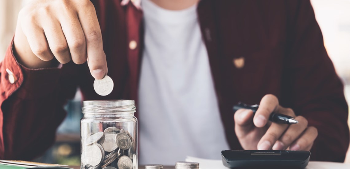 man putting money in a savings jar
