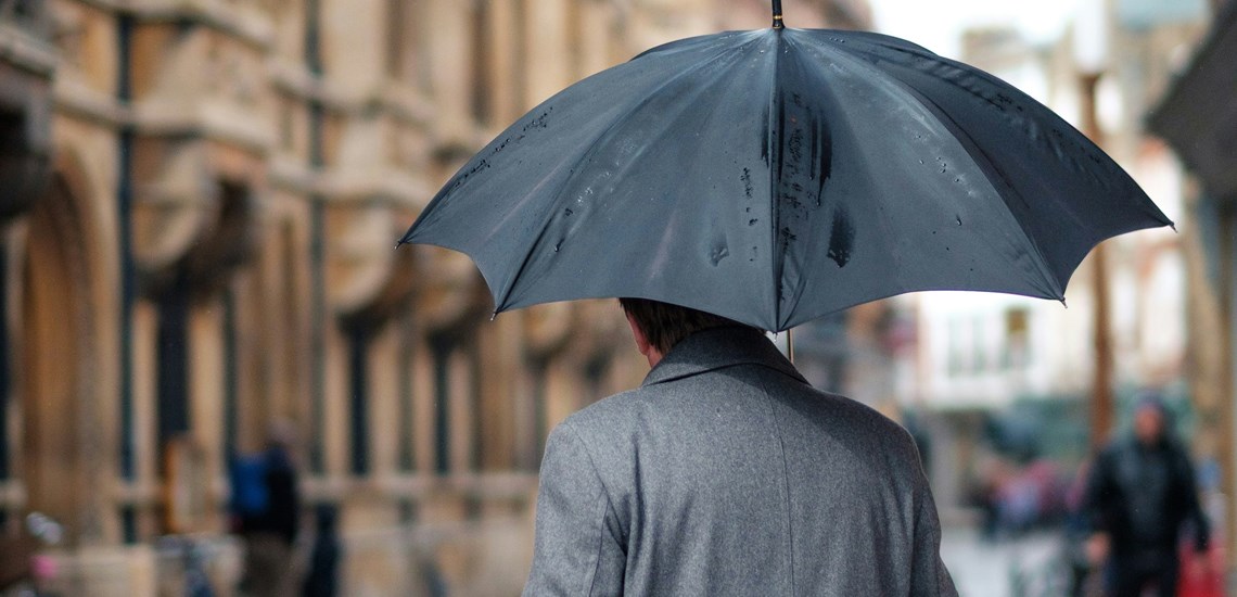 man-walking-umbrella-rain-protection-weathering-the-storm